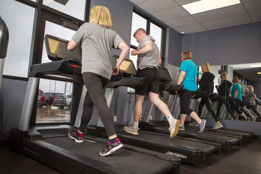 Four people using treadmills at a gym