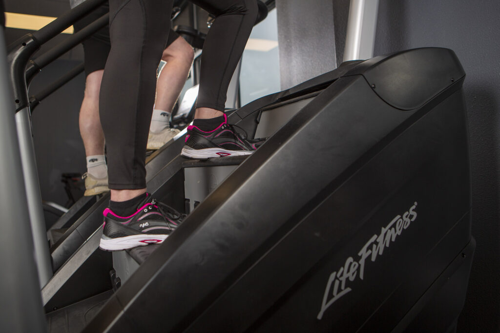 Two people using stair machines at a gym