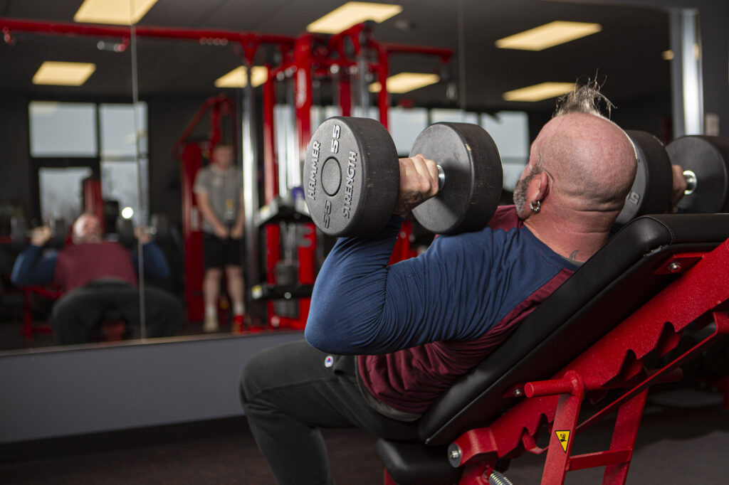 Gym-goer laying back and lifting a set of 55 pound weights