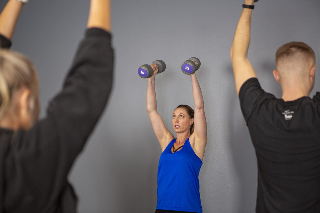 Fitness instructor lifting 15 pound weights over her head