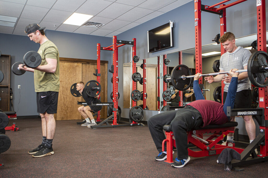 Four gym-goers lifting weights and exercising